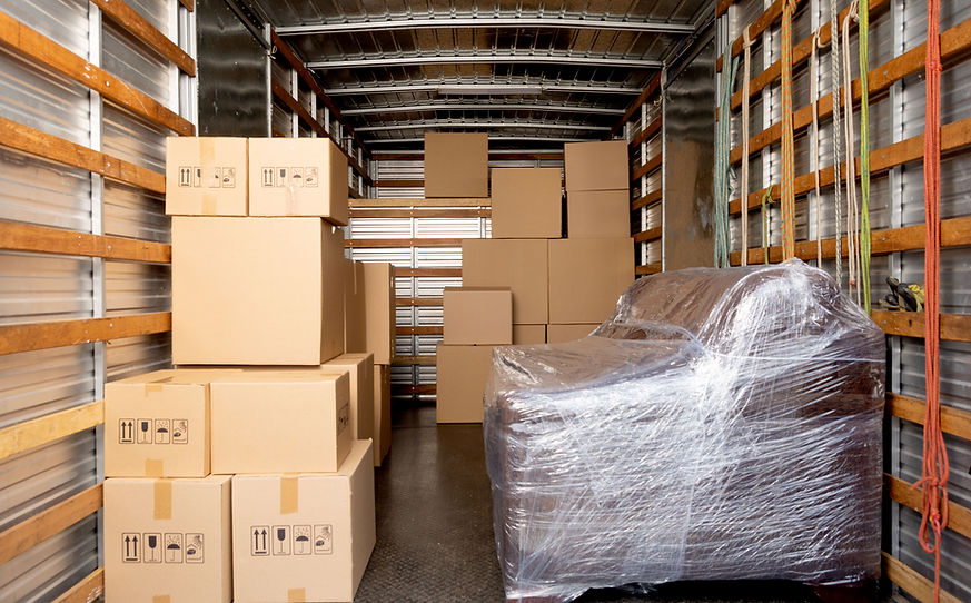Fully Loaded Moving Truck Interior Interior of a moving truck filled with cardboard boxes and a wrapped couch ready for transport.