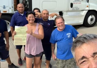 Group of people smiling in front of a Terry Moving & Storage truck, one woman holding official moving paperwork.