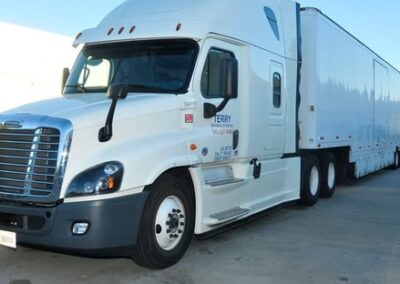 Large white Terry Moving & Storage semi-truck parked on a clean concrete lot under a clear blue sky.