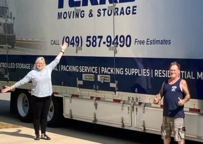 Happy customers standing in front of a Terry Moving & Storage truck with arms raised.
