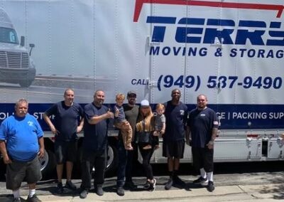 Terry Moving & Storage team posing with a family in front of their branded moving truck.