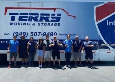 Group of Terry Moving & Storage team members standing in front of a branded moving truck on a sunny day.