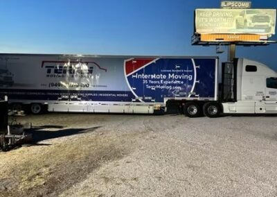 Terry Moving & Storage interstate truck parked under a billboard during twilight.