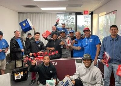 Group of employees inside an office room celebrating and holding various boxed prizes and gifts.