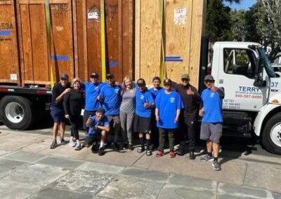 Terry Moving & Storage team posing in front of a truck and large wooden moving crates.