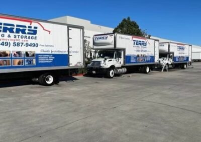 Three moving trucks from Terry's Moving and Storage parked in a lot with clear branding.