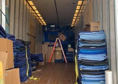 Inside view of a moving truck with stacks of folded moving blankets and boxes organized along the walls.