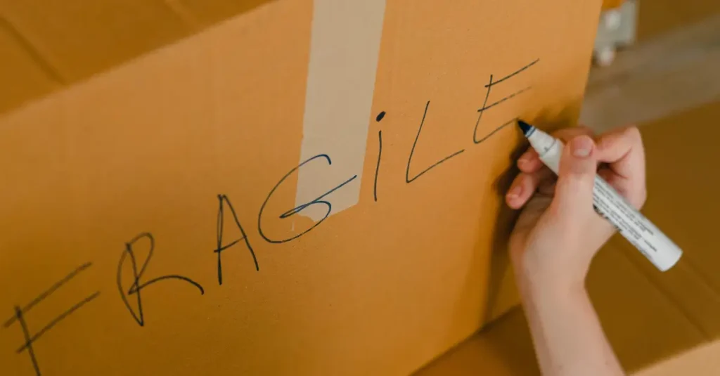 Person labeling a moving box as fragile.