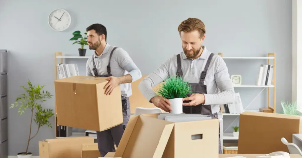 Professional movers packing boxes and office items